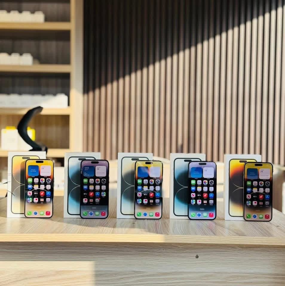 Five iPhones powered on with display screens alongside packaging on showroom counter